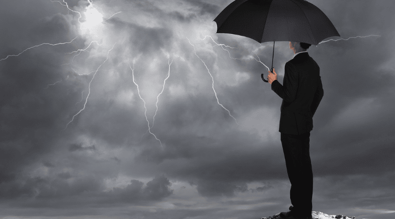 Business man in a suit and holding an umbrella in a thunderstorm