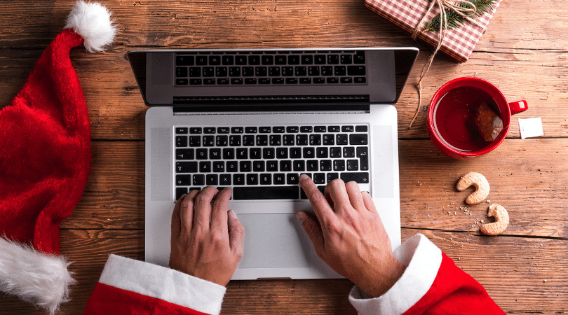 Close up the hands of a person in a Santa suit typing on a laptop